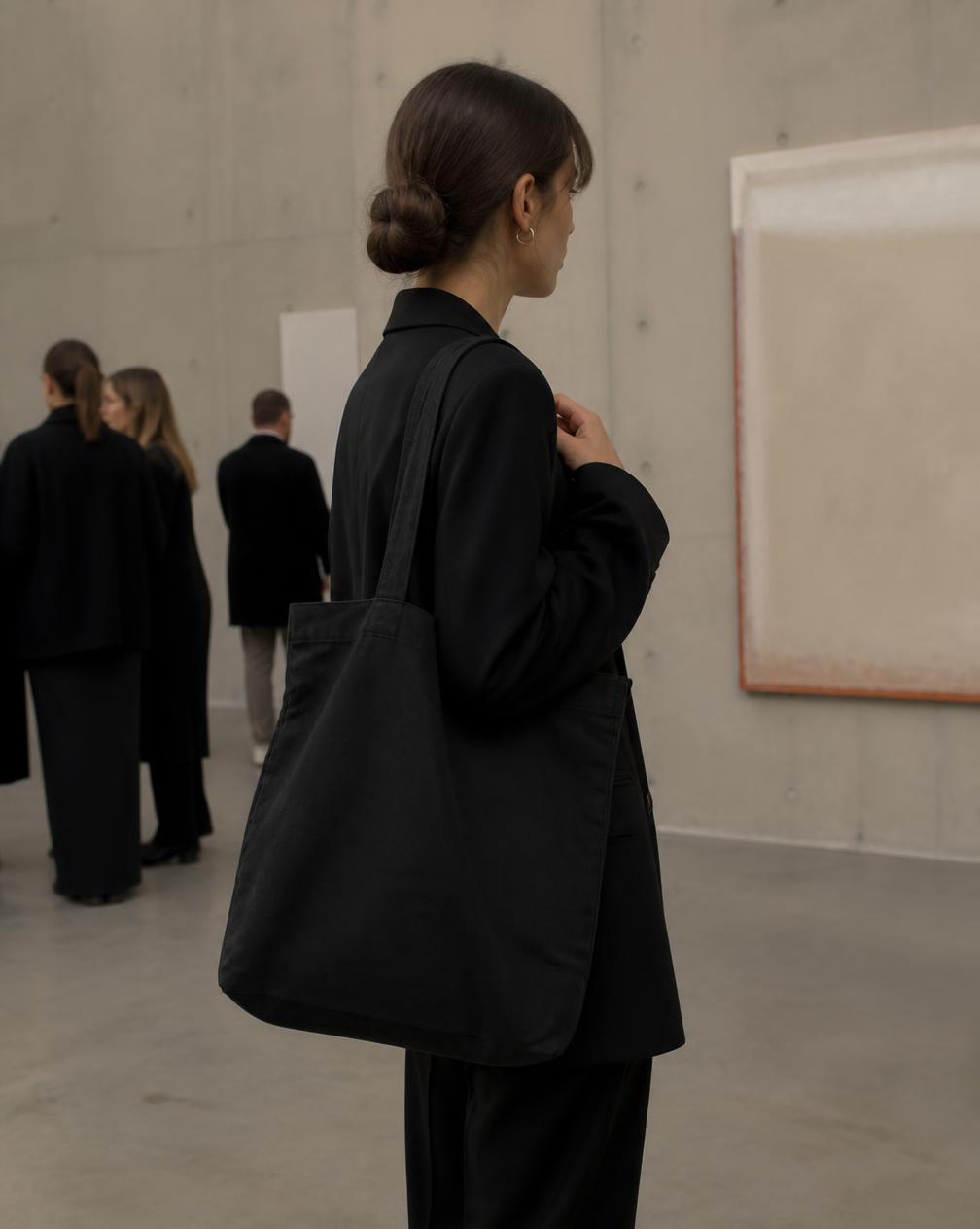 Black canvas tote bag carried at a gallery opening
